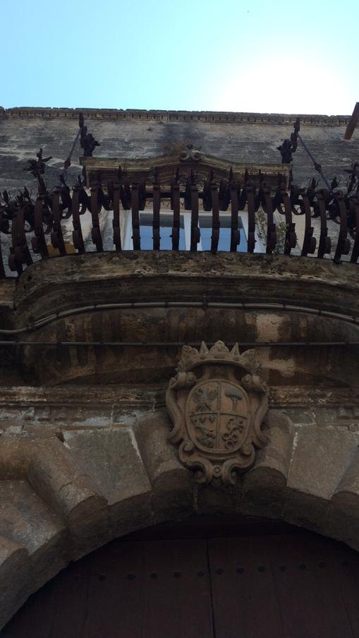 Wrought-iron balcony and stone coat of arms above a portal in the old town, Manduria, Salento, Puglia