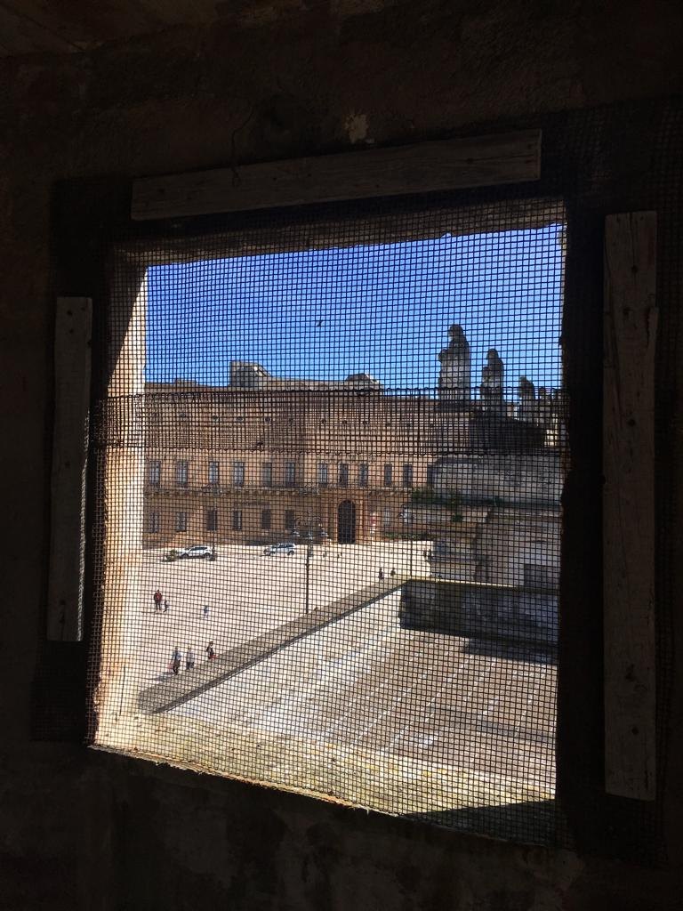 The piazza seen through the mesh of a building site window, Manduria, Salento, Puglia