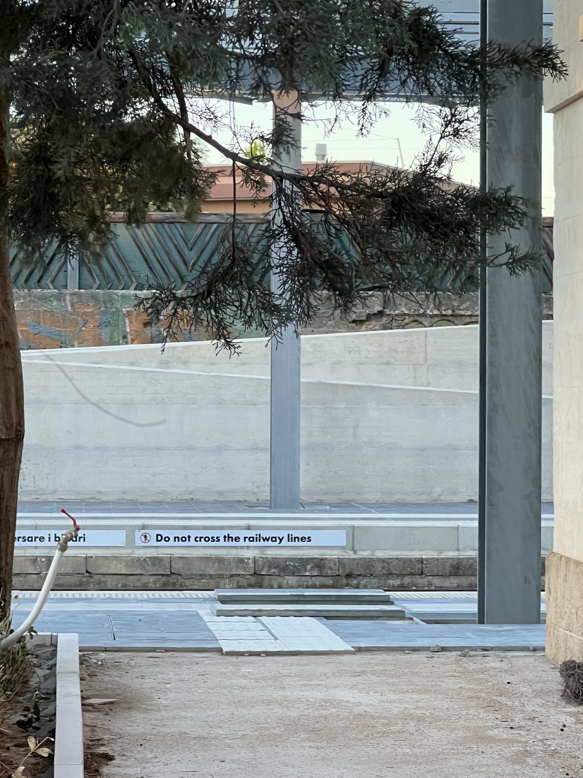 Il cartello di sicurezza bilingue sulla nuova banchina della stazione di Manduria, con la scritta in inglese Do not cross the railway lines accanto al testo italiano